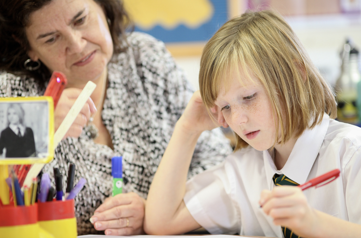 Teacher supporting a pupil with writing